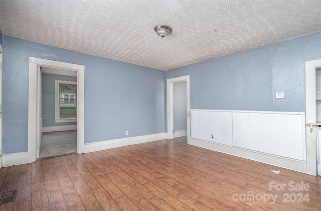 spare room featuring hardwood / wood-style floors and a textured ceiling