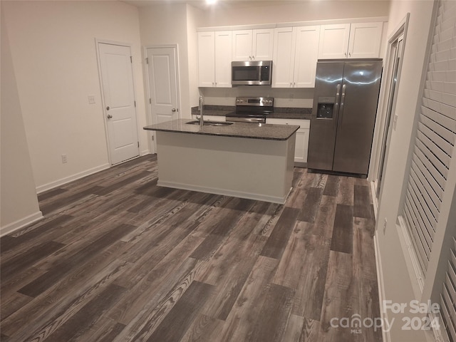 kitchen with sink, an island with sink, appliances with stainless steel finishes, dark hardwood / wood-style flooring, and white cabinetry