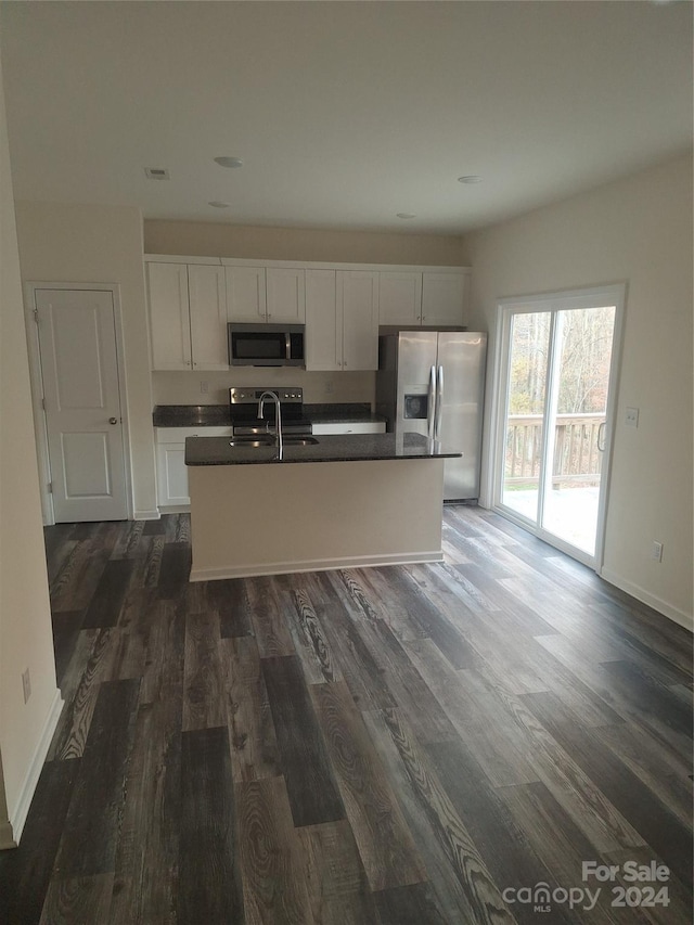 kitchen featuring appliances with stainless steel finishes, sink, a center island with sink, white cabinets, and dark hardwood / wood-style floors