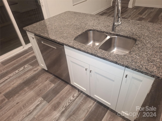 kitchen with dark stone countertops, dishwasher, sink, and white cabinets