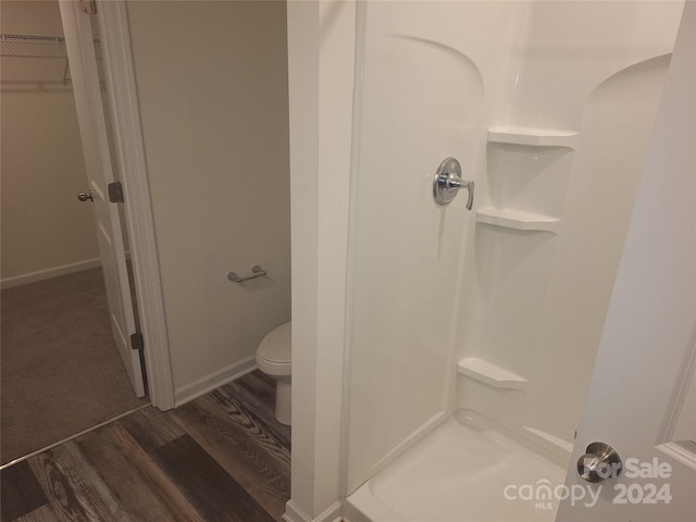 bathroom with walk in shower, toilet, and hardwood / wood-style flooring