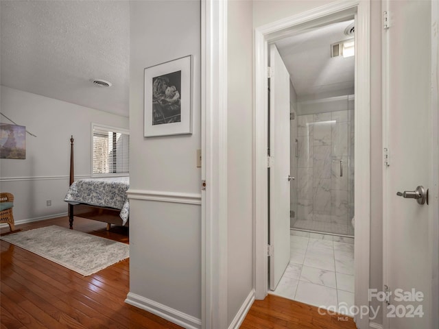 hall with a textured ceiling and light hardwood / wood-style floors