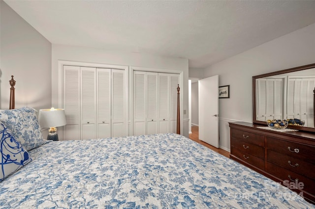 bedroom with multiple closets, hardwood / wood-style floors, and a textured ceiling