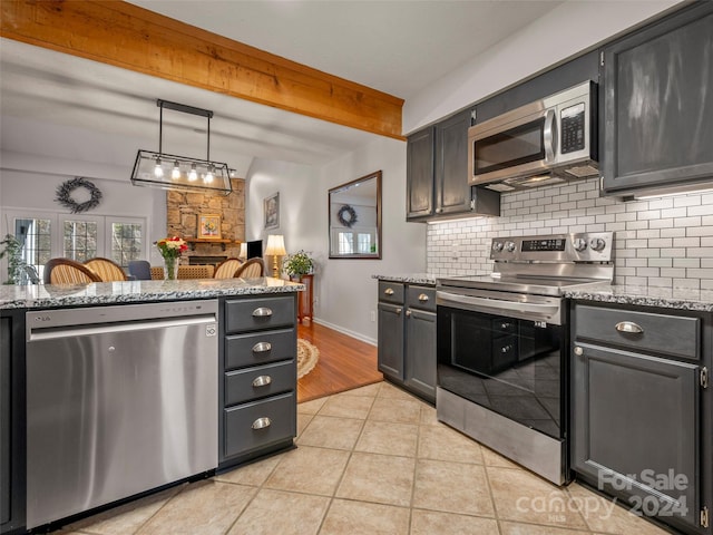 kitchen featuring light stone countertops, light tile patterned floors, appliances with stainless steel finishes, tasteful backsplash, and decorative light fixtures