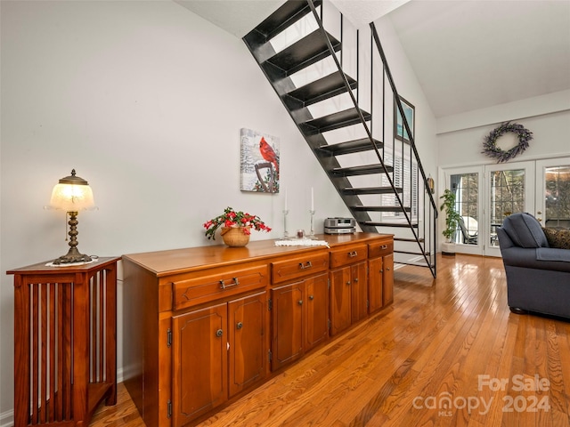 bar featuring french doors, light hardwood / wood-style floors, and high vaulted ceiling