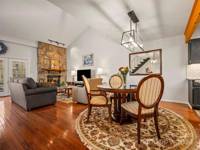 dining room with a notable chandelier, dark hardwood / wood-style floors, a fireplace, and vaulted ceiling