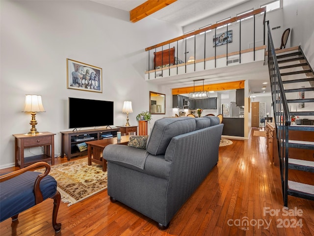 living room featuring beam ceiling, wood-type flooring, and a towering ceiling