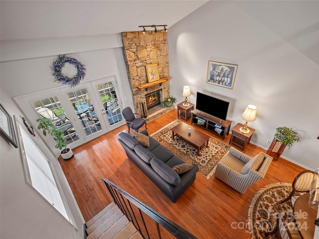 living room featuring hardwood / wood-style flooring, a fireplace, high vaulted ceiling, and french doors