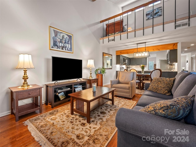 living room with wood-type flooring and a towering ceiling