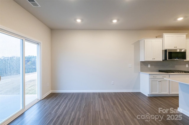 kitchen with white cabinets, gas cooktop, tasteful backsplash, and dark wood-type flooring