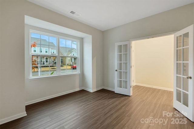 empty room with french doors and hardwood / wood-style flooring