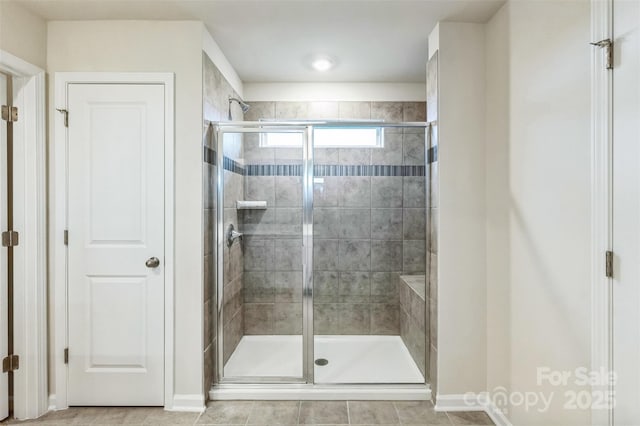 bathroom with a shower with door and tile patterned flooring