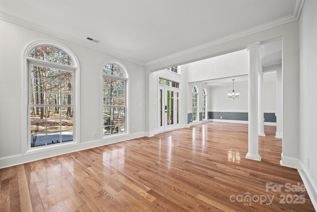 unfurnished living room featuring ornamental molding, decorative columns, and a chandelier