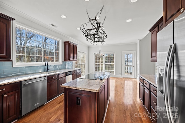 kitchen featuring sink, a center island, pendant lighting, a notable chandelier, and appliances with stainless steel finishes