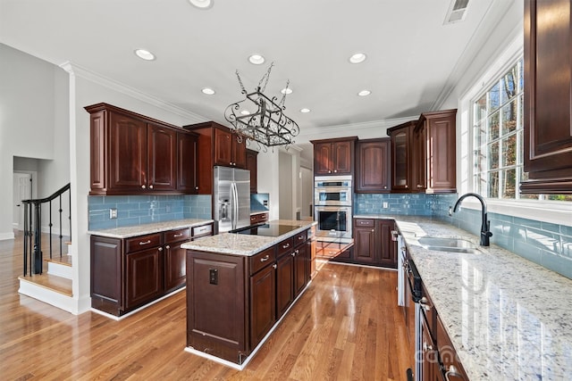 kitchen featuring a center island, stainless steel appliances, light hardwood / wood-style floors, crown molding, and sink