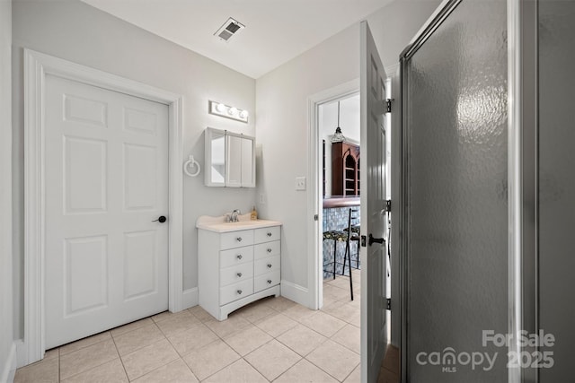 bathroom featuring tile patterned flooring, a shower with shower door, and vanity