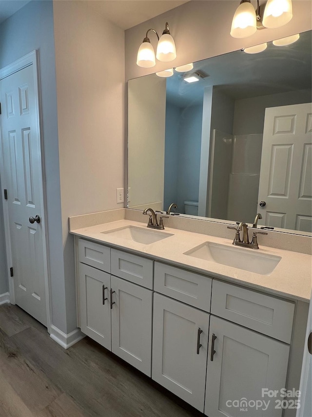 718 Park Ave, Salisbury, NC 28144 - bathroom featuring wood finished floors, double vanity, toilet, and baseboards