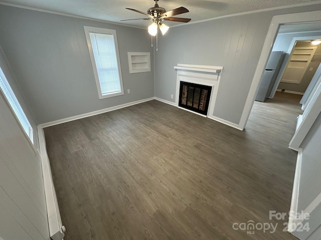 unfurnished living room with ceiling fan, ornamental molding, and dark wood-type flooring