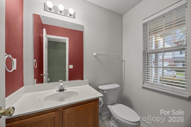 bathroom featuring vanity, a healthy amount of sunlight, a textured ceiling, and toilet