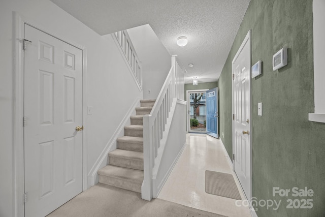 stairs with carpet and a textured ceiling