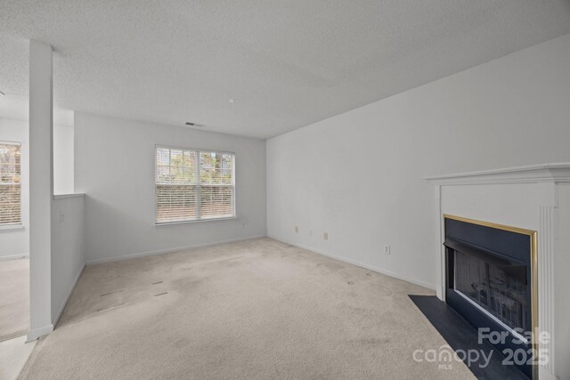 unfurnished living room with light colored carpet and a textured ceiling