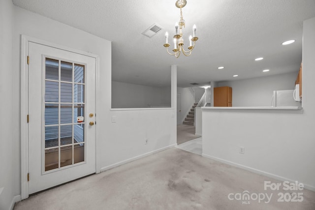 interior space with light carpet, a chandelier, and a textured ceiling