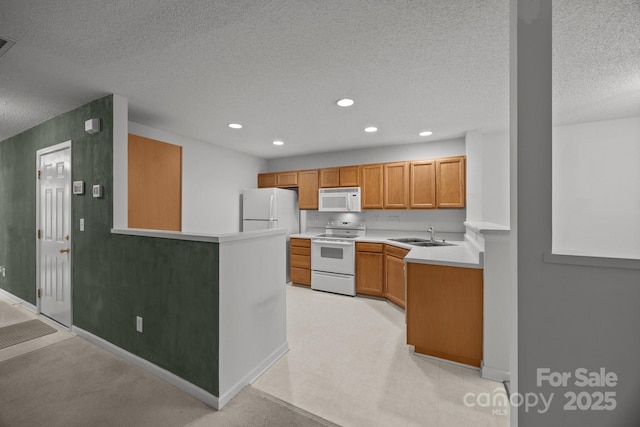 kitchen with sink, white appliances, kitchen peninsula, and a textured ceiling