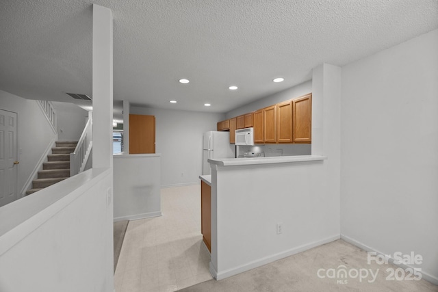 kitchen with white appliances, kitchen peninsula, and a textured ceiling