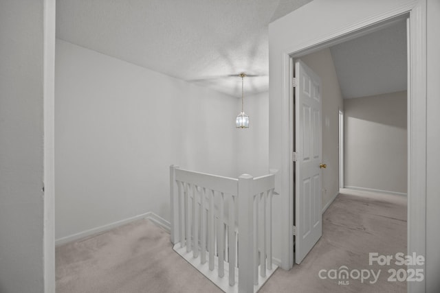 hallway featuring light carpet and a textured ceiling