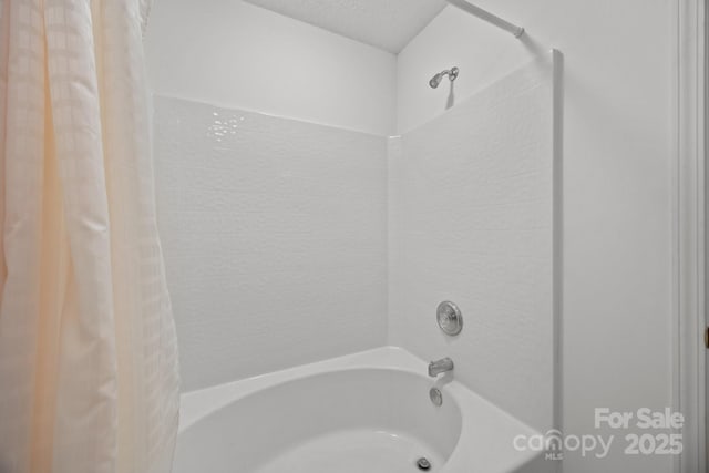 bathroom featuring shower / bathtub combination with curtain and a textured ceiling