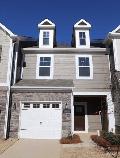 view of front of property featuring concrete driveway, a garage, and stone siding