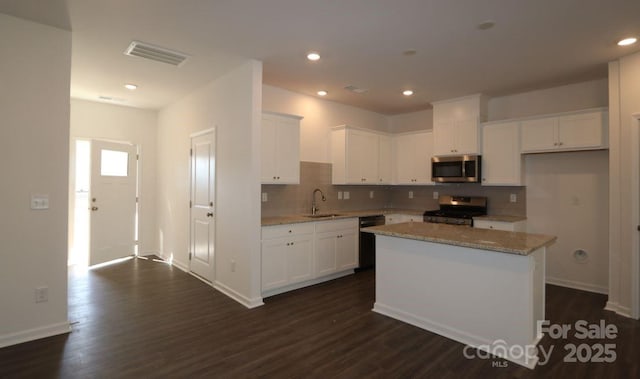 kitchen featuring visible vents, dark wood-type flooring, white cabinets, stainless steel appliances, and a sink