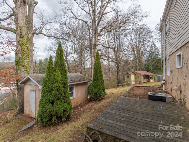 exterior space with central air condition unit, a deck, and a storage unit