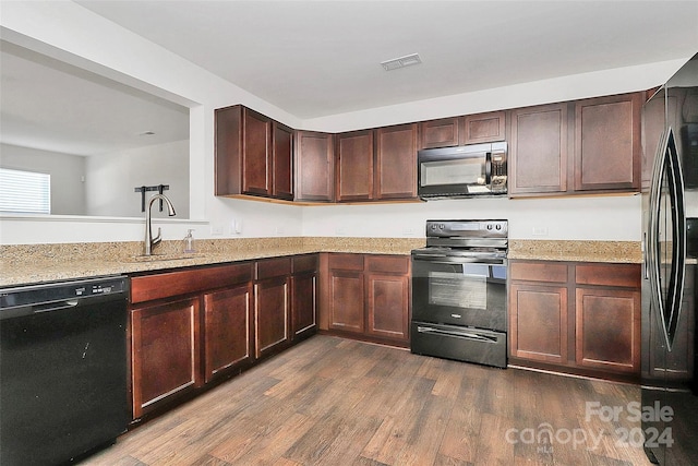 kitchen featuring light stone counters, sink, black appliances, and dark hardwood / wood-style floors