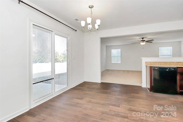 unfurnished living room with plenty of natural light, ceiling fan with notable chandelier, and dark hardwood / wood-style floors