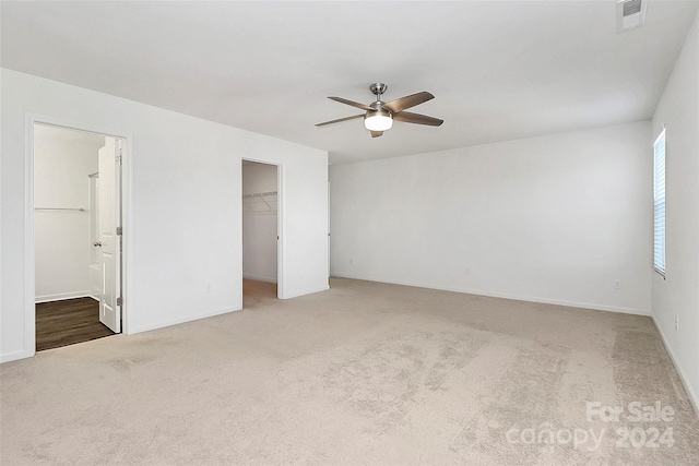 unfurnished bedroom featuring carpet flooring, a walk in closet, ensuite bathroom, ceiling fan, and a closet