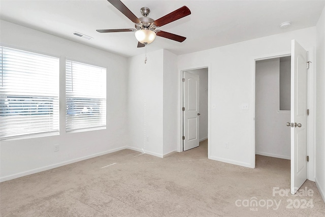 unfurnished bedroom featuring ceiling fan, a closet, and light colored carpet