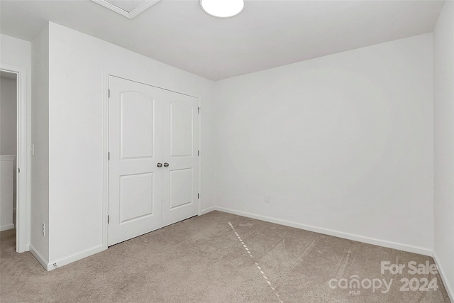 unfurnished bedroom featuring a closet and light colored carpet