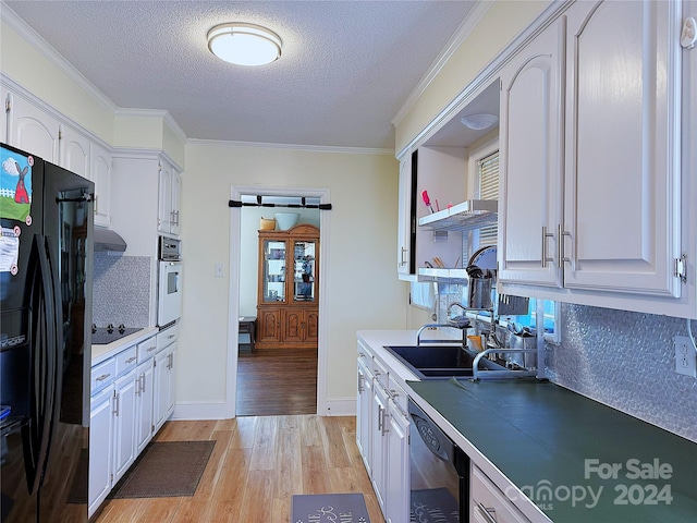 kitchen featuring ornamental molding, a textured ceiling, black appliances, white cabinets, and light hardwood / wood-style floors