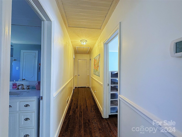 corridor with dark hardwood / wood-style flooring, crown molding, and sink