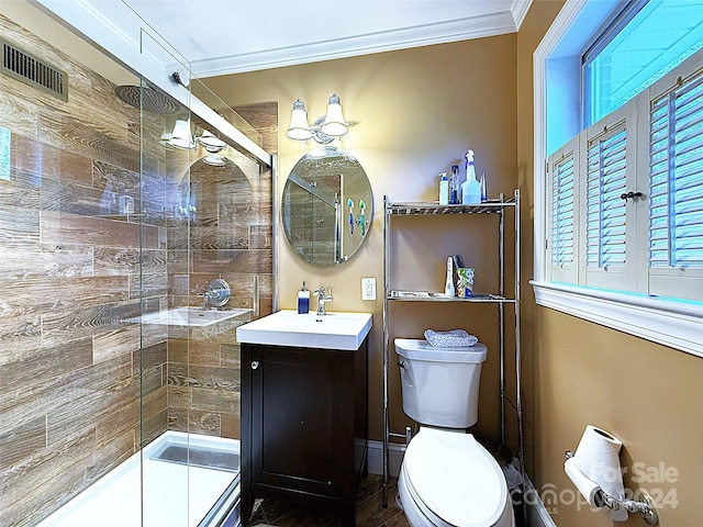 bathroom featuring ornamental molding, vanity, toilet, and a shower with shower door