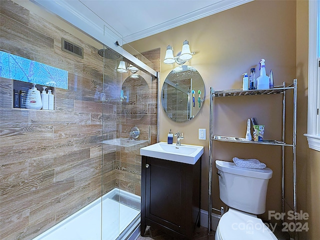 bathroom featuring crown molding, vanity, a shower with shower door, and toilet