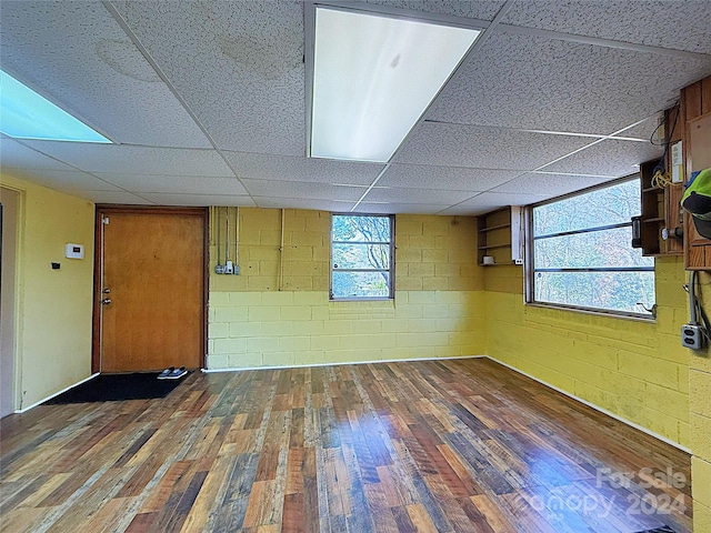 spare room with dark hardwood / wood-style flooring and a drop ceiling