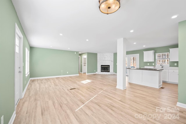 unfurnished living room featuring a brick fireplace and light wood-type flooring