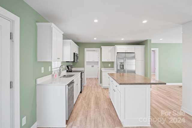 kitchen featuring stainless steel appliances, a kitchen island, and white cabinetry