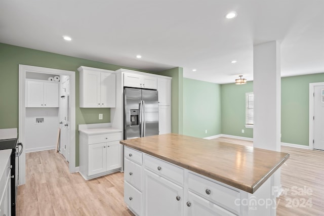 kitchen featuring white cabinetry, stainless steel fridge, a kitchen island, and light wood-type flooring