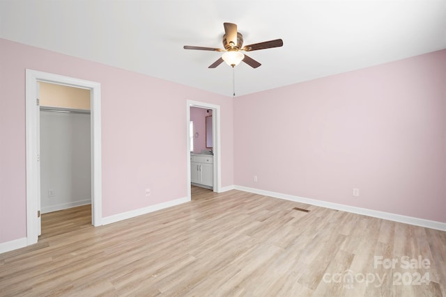 unfurnished bedroom with ceiling fan, light wood-type flooring, a spacious closet, and a closet