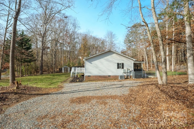 view of side of property featuring a lawn, central AC unit, and a storage unit