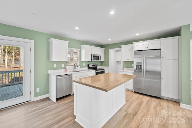 kitchen with sink, white cabinets, a center island, stainless steel appliances, and light hardwood / wood-style flooring