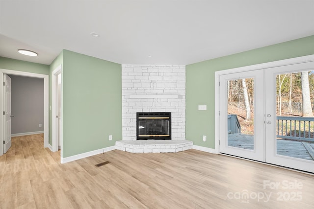 unfurnished living room with light hardwood / wood-style flooring, a fireplace, and french doors